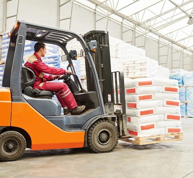 A man driving a forklift in an industrial setting.