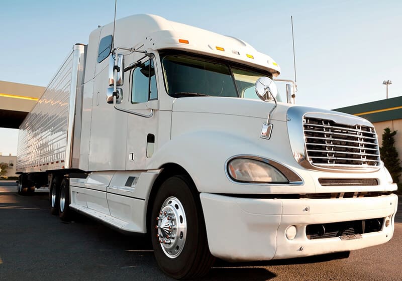 A white semi truck is parked on the side of the road.