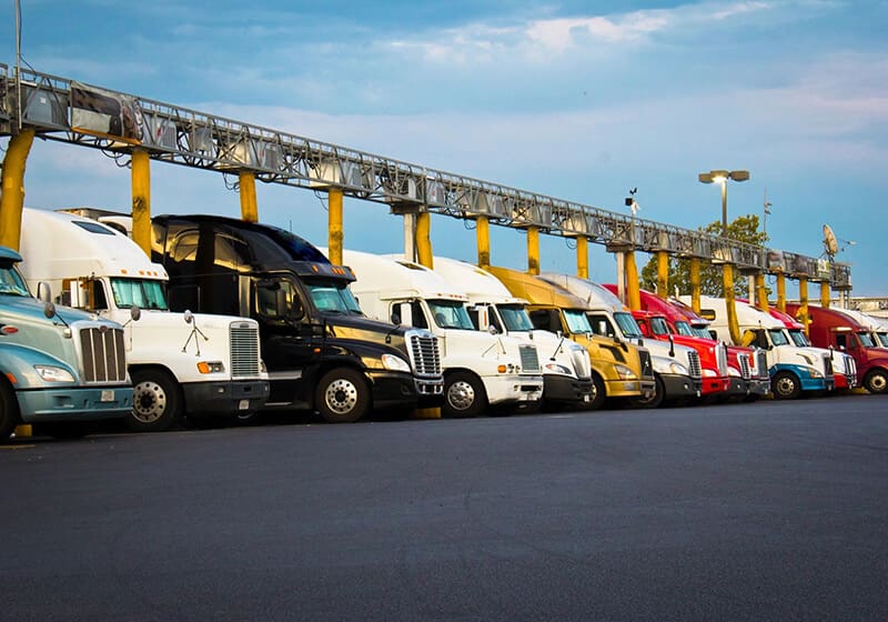 A line of trucks parked in front of a yellow gate.