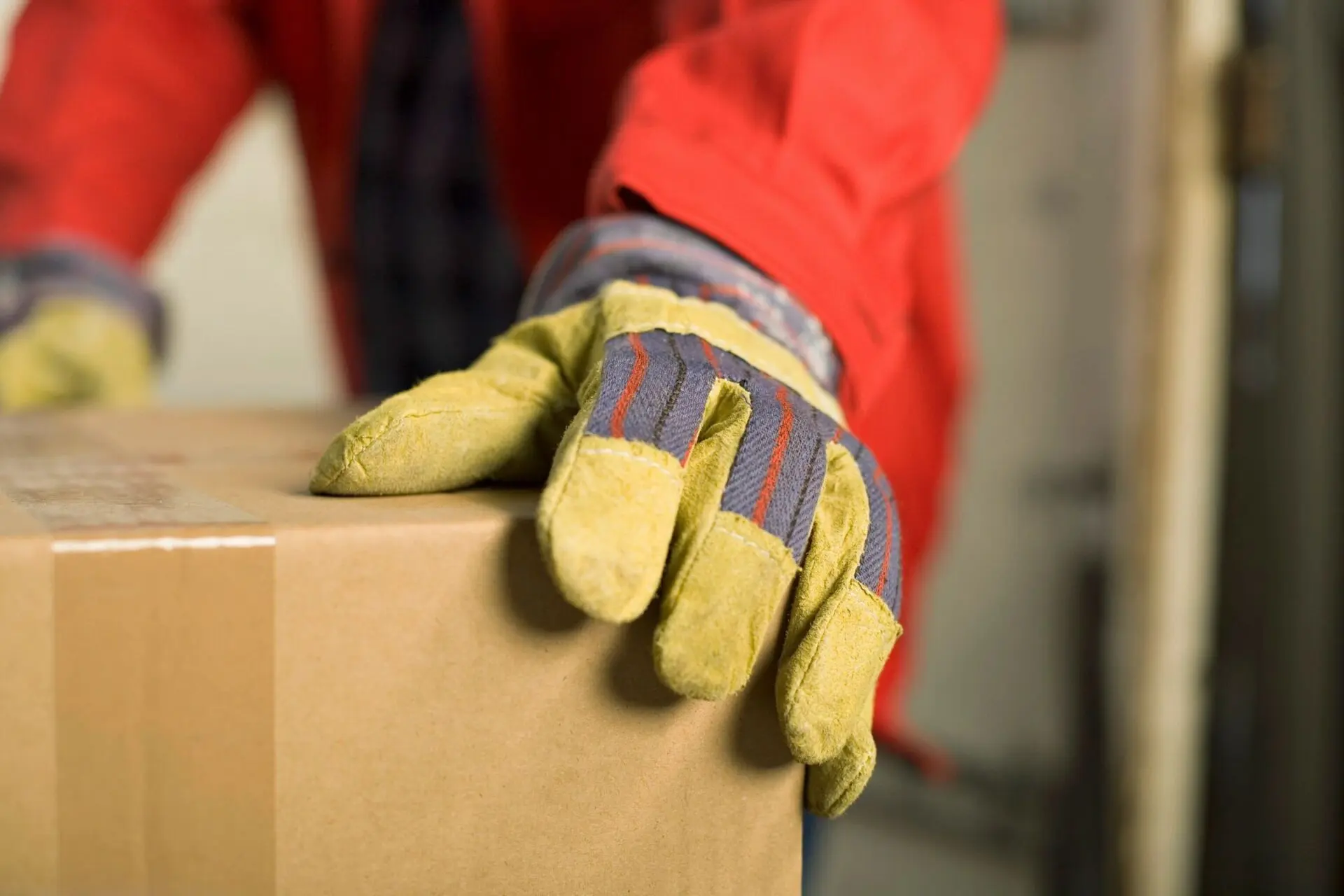 A person wearing gloves and holding onto boxes.